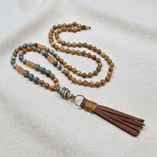 מאלה 'רחש העץ' מונחת על בד טבעי, שרשרת מאלה אבני חן עם ג'ספר זברה ירוק, ווד גריין ג'ספר וקרנליאן כתום וגדיל חום דמוי זמש