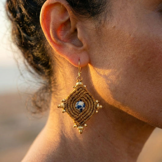 עגילי הופי חום תקריב על אוזן דוגמנית, גספר דלמטי מרכזי מוקף מקרמה וחרוזי בראס עדינים