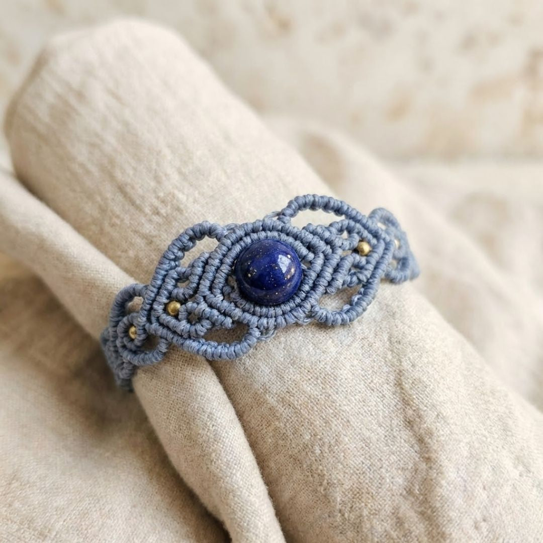 צמיד 'גאיה' כחלחל עם לאפיס וחרוזי בראס על בד פשתן בהיר, דגש על סריגת חוט השעווה