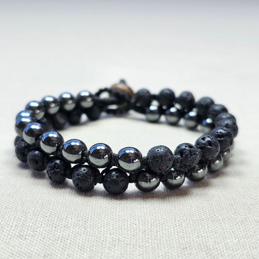 תקריב צמיד מקרמה עם אבני בזלת והמטייט מונח על בד בגוון טבעי, שילוב אבנים שחורות ומטאליות