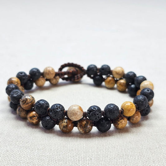 תקריב צמיד מקרמה עם אבני בזלת שחורות ופיקצ'ר ג'ספר בגווני אדמה על בד בגוון טבעי