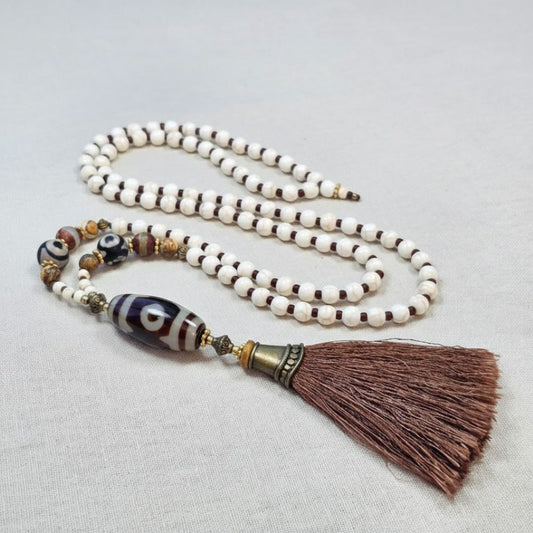שרשרת מאלה 'עין פנימית' מונחת על בד טבעי, מאלה אבני חן עם היולייט, חרוזי אגת טיבטי, פיקצ'ר ג'ספר וגדיל חום