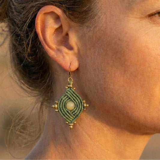 עגילי הופי ירוק מרווה תקריב על אוזן דוגמנית, אבן סיטרין מרכזית מוקפת מקרמה וחרוזי בראס עדינים