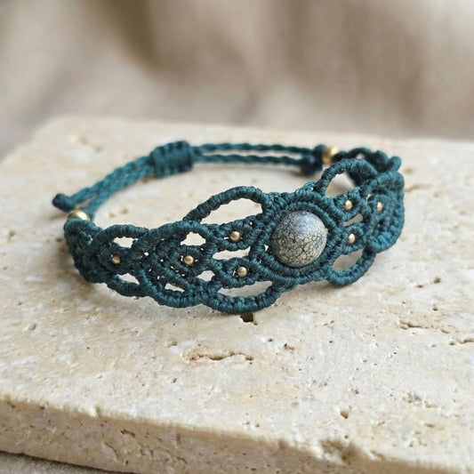 צמיד מקרמה 'גאיה' ירוק עם ג'ספר זברה ירוק על משטח אבן בהיר, דגש על מבנה הצמיד