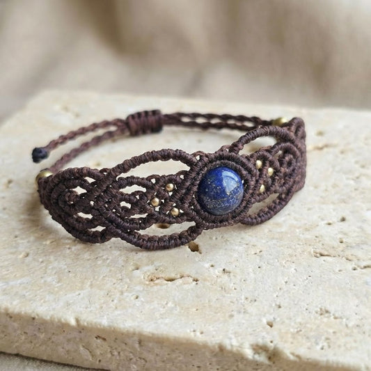 צמיד מקרמה 'גאיה' חום עם לאפיס לזולי על משטח אבן בהיר, סריגת חוט שעווה מודגשת