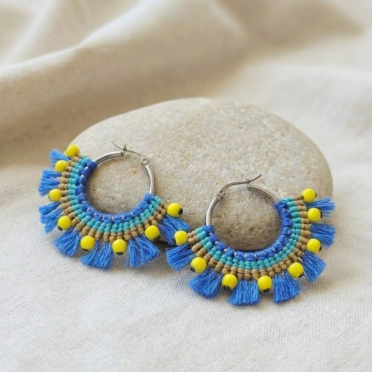 עגילי מקרמה אפריקה כחול וצהוב עם חרוזי היולייט על חישוק כסף מונחים על אבן טבעית ובד בהיר