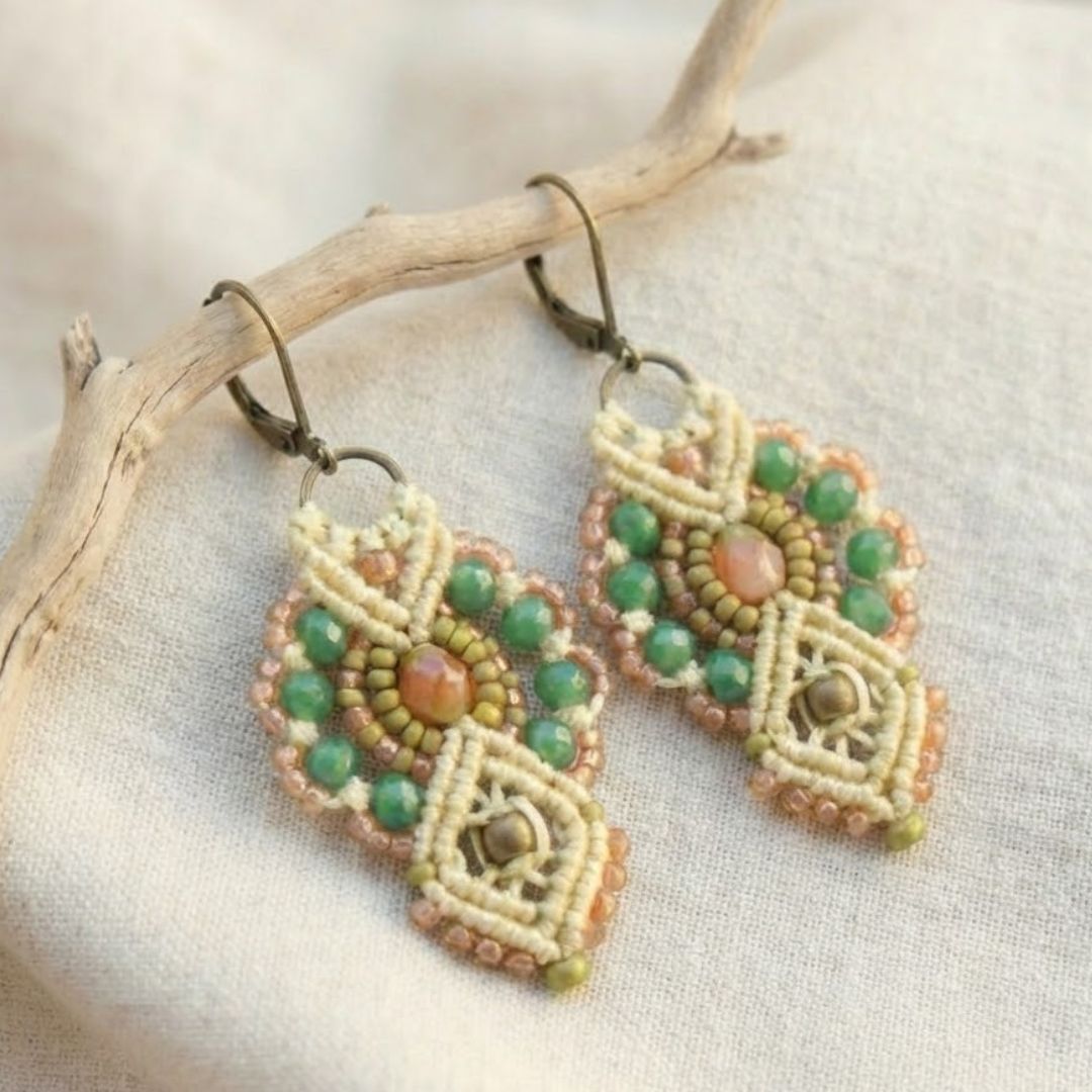 עגילי מקרמה אינקה שמנת וירוק בזווית על בד פשתן בהיר