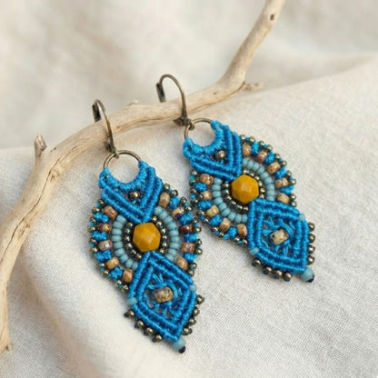 עגילי מקרמה אינקה טורקיז וחרדל בזווית על בד פשתן בהיר