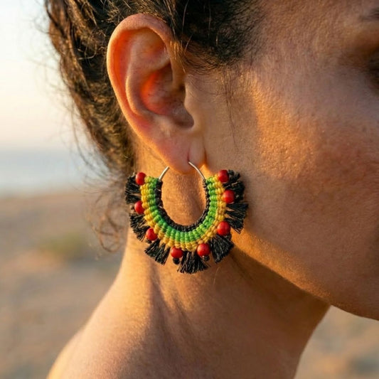 עגילי מקרמה אפריקה בגווני רסטה עם חרוזי היולייט על חישוק כסף קלוזאפ על דוגמנית ברקע מדברי