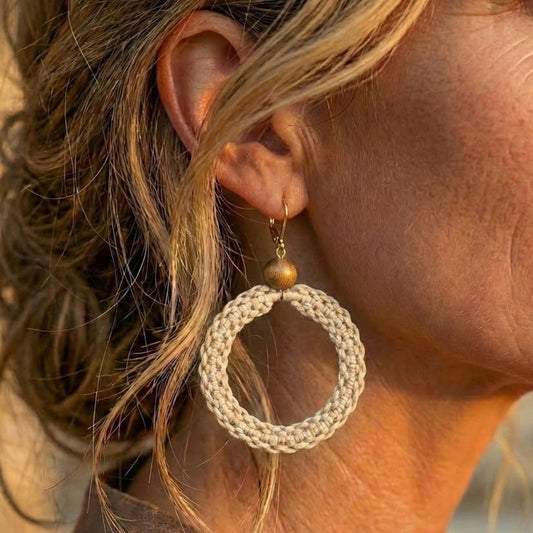 תקריב עגיל 'שיבטה' בז' טבעי על האוזן, טקסטורת סריגת חוט שעווה מודגשת וחרוז עץ כהה