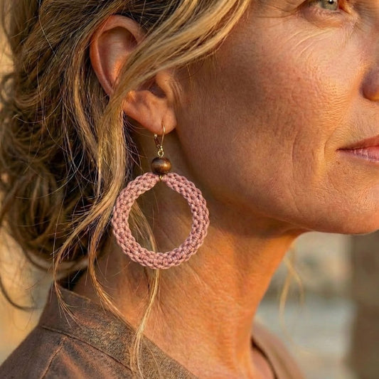 תקריב עגיל 'שיבטה' ורוד עתיק על האוזן, טקסטורת סריגת חוט שעווה מודגשת וחרוז עץ כהה